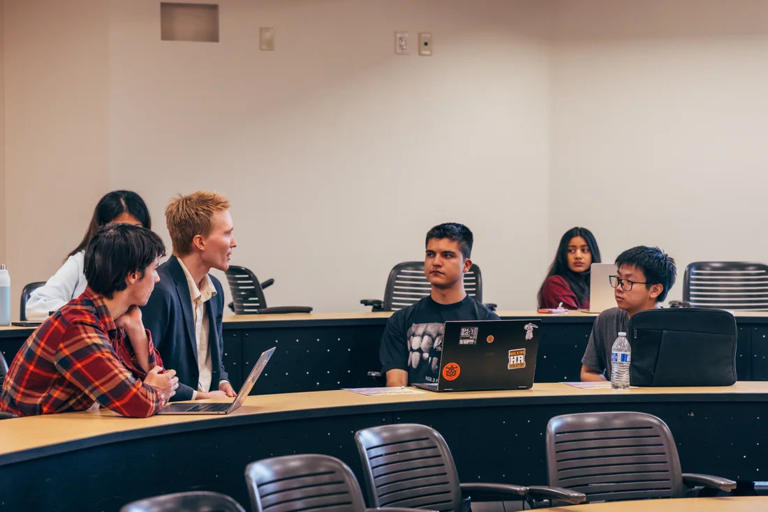 A facilitator and participants discuss their work together around laptops in the classroom.