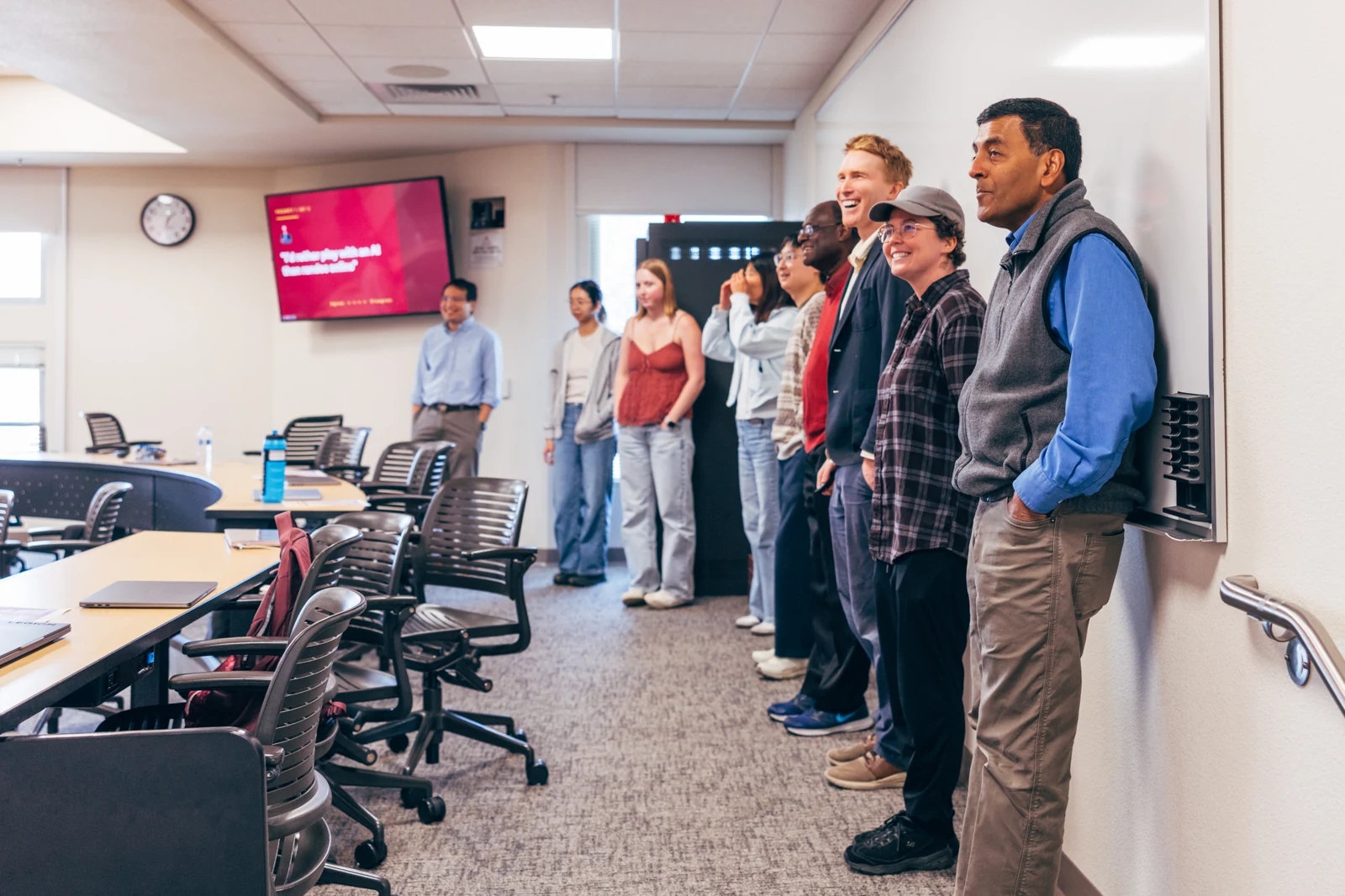 AI Kitchen participants stand together along the classroom wall, smiling during a session.