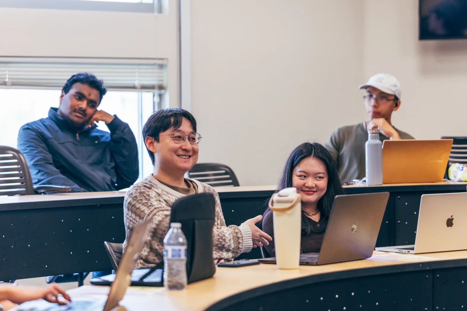 AI Kitchen participants smiling and sharing ideas with laptops open during a session.